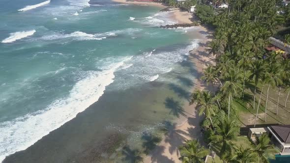 Blue Ocean Waves with White Foam Roll on Sandy Coastline