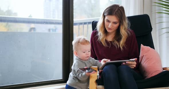 Mother using digital tablet while tacking care of her baby 4k