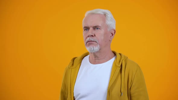 Gray-Haired Pensioner Showing Face-Palm Gesture Against Orange Background, Fail