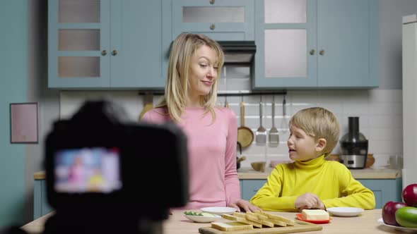 Young Woman Teaches Boy How to Make Sandwiches and Filming Video with Camera