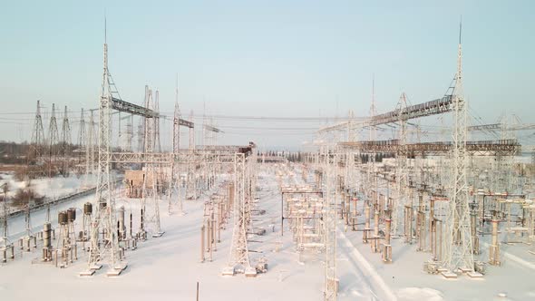 Aerial View of an Electrical Substation in Winter with High Pylons and Voltage Distribution Cables