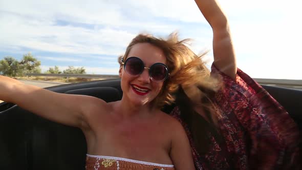 Two beautiful female friends riding in the back seat of convertible