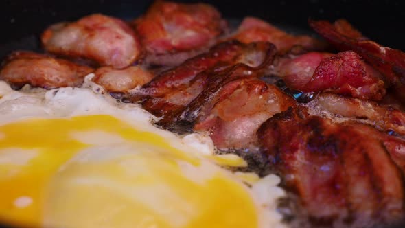 Frying crispy bacon and an egg in a pan. Cooking meat.