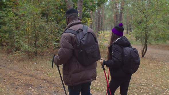 Interracial Couple with Backpacks Trekking in Wood