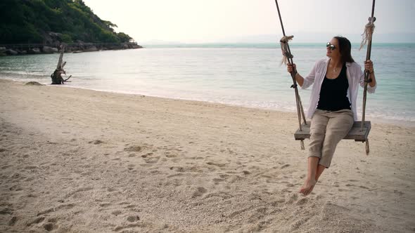 A Young Woman Swinging on a Swing on the Beach