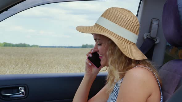 Blonde Girl Sits in Car Smiles Speaks on Cellphone