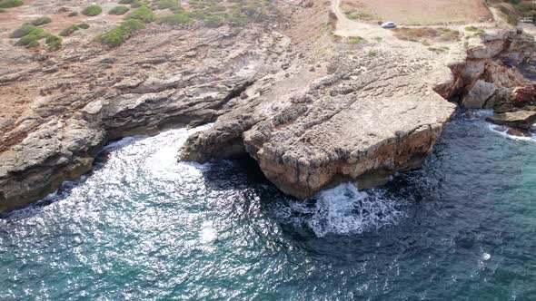 Aerial top view waves break on rocks in a blue ocean. Sea waves on beautiful beach aerial