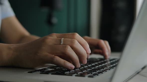 Lady in White Blouse Types on Grey Laptop Keyboard Buttons