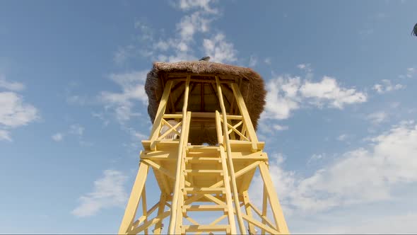 Looking up at a bright yellow watch tower on a tropical beach. Footage in slow motion.