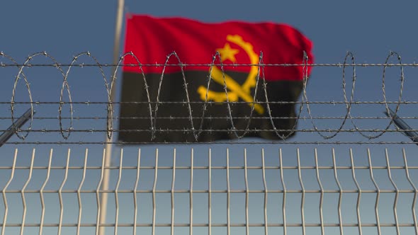 Waving Flag of Angola Behind Barbed Wire Fence
