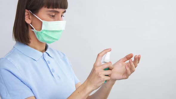 Woman in Sterile Mask Using Hand Antibacterial Spray Sanitizer To Avoid Virus