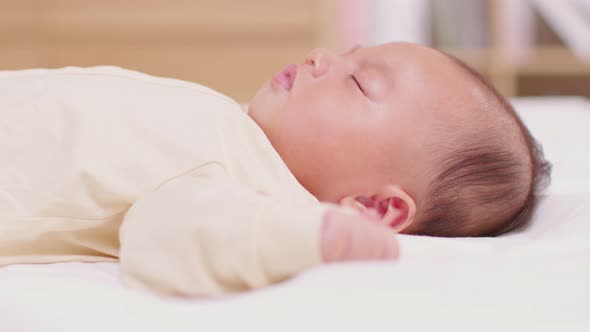 Top view happy newborn baby lying and sleep on a white bed and blanket comfortable