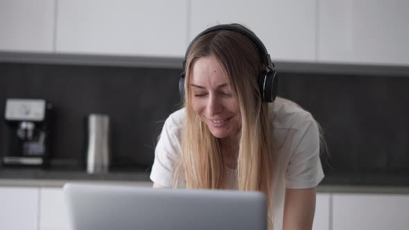 Woman Using Laptop Wearing Headphones at Home