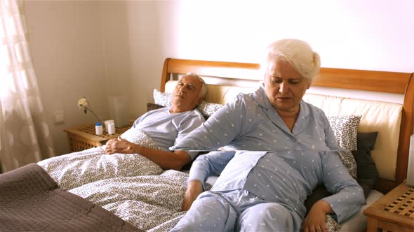 Senior woman suffering from backache sitting on bed