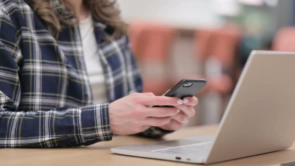 Female with Laptop Using Smartphone Close Up