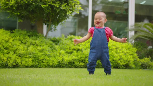 Close Up of Happy Girl Toddler Outdoor Takes the First Steps and Falls