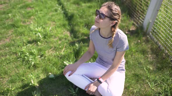 Portrait of an Attractive Smiling Caucasian Woman in a Park with Glasses