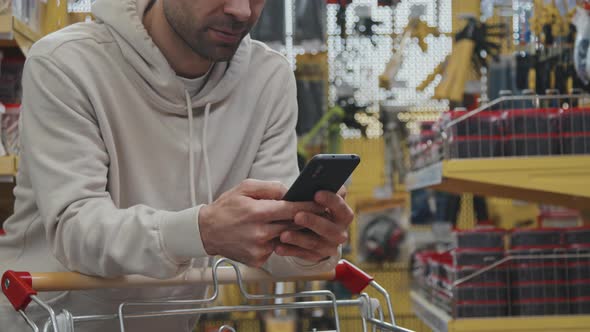 Slowmo of Man Texting on Phone at Hardware Store