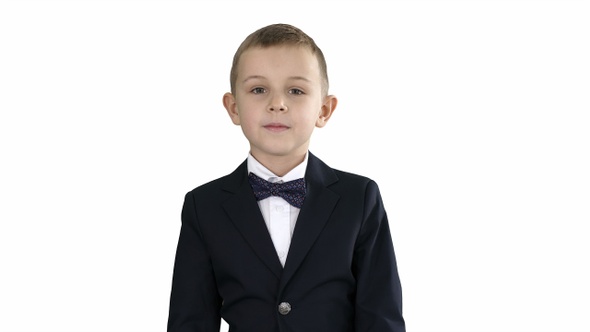 Little boy in a costume with a bow tie walking on white background