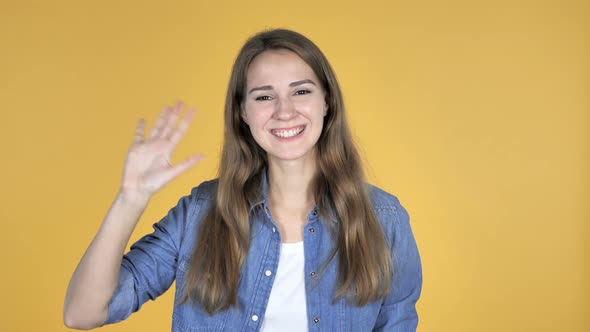 Pretty Woman Waving Hand To Welcome Isolated on Yellow Background