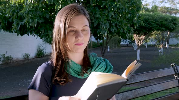 Young caucasian student woman slowly turns page of book outdoors. Education concept. Slow motion.