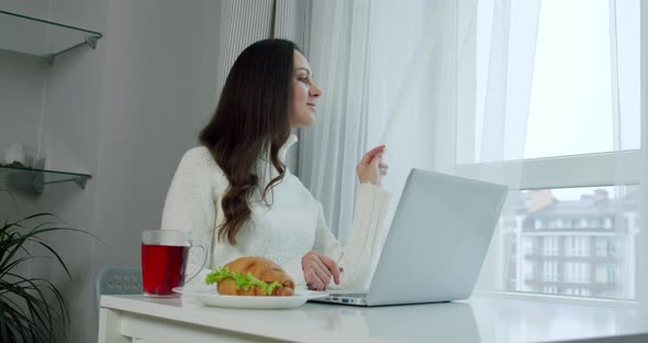 Female Sitting Table Looking Out Window Table Laptop Tea Croissant Slow Motion