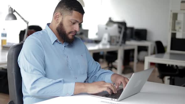 Serious Focused Male Manager Using Laptop at Workplace