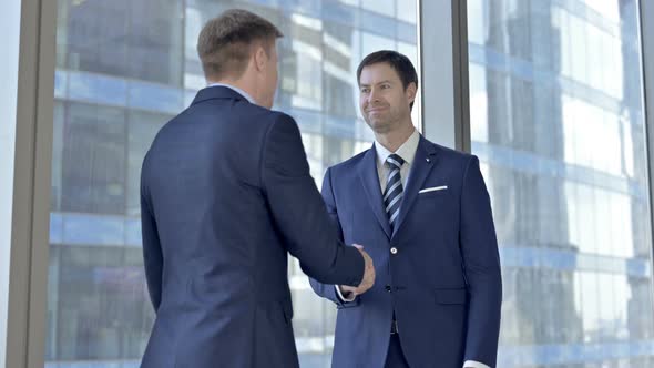 Middle Aged Businessmen Shaking There Hands and Having Conversation in Boardroom