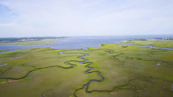 Drone flying over green wetlands near the ocean