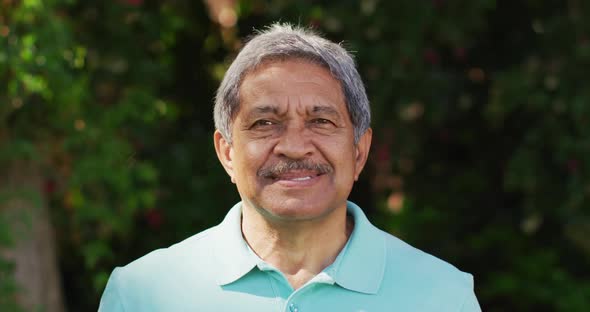 Video of happy biracial senior man looking at camera in garden