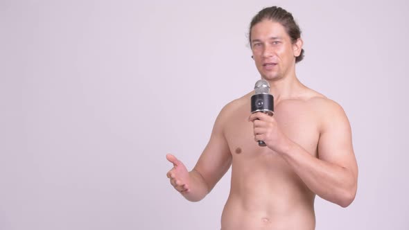 Muscular Shirtless Man Presenting Something with Microphone