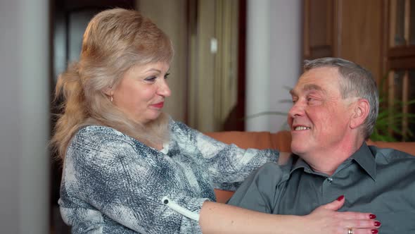 Cheerful old elderly adult family couple hugging laughing bonding looking at camera