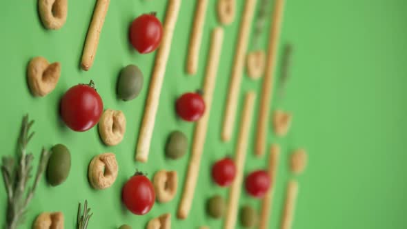 Vertical video: pattern of italian pastries, italian bread sticks, olives, cherry tomatoes, rosemary