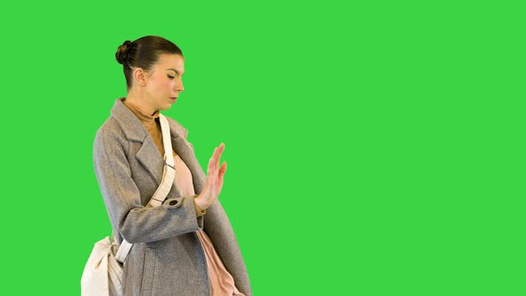 Young Woman in Grey Coat Stands Dancing on a Green Screen Chroma Key