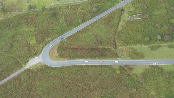 Aerial drone view following traffic on a narrow, winding mountain road