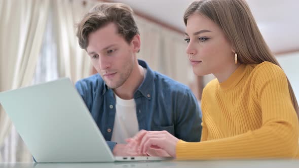 Attractive Couple Celebrating Online Payment Success on Laptop