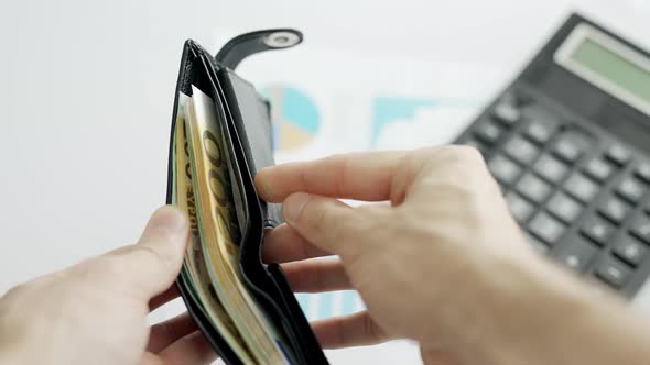 A Businessman Hands are Counting Euro Bill Notes on Background of Calculator and Graphs