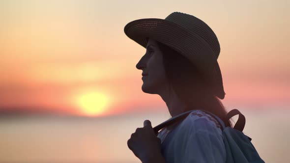 Smiling Travel Woman in Hat Admiring Amazing Scarlet Sunset Over Sea Dreaming and Relaxing