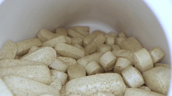 Prescription Drug Bottle Filled with Beige Pills Slow Motion on Slider with Camera Macro Lens