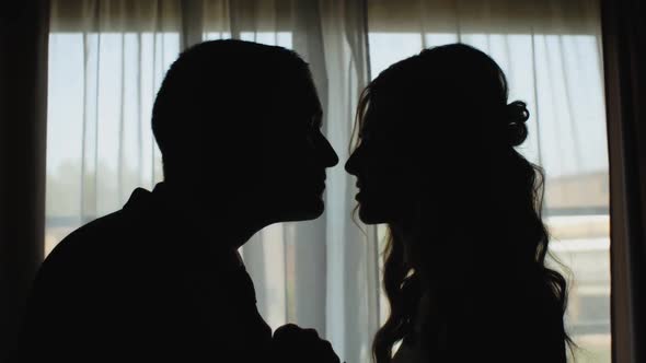 Silhouette of a Man and Woman in Love Kissing By the Window
