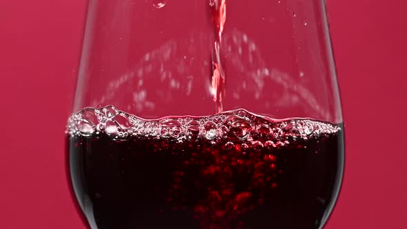 Close up pouring red wine in wineglass over red