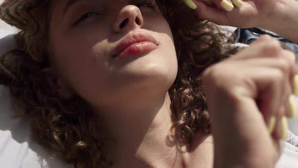 Portrait Sleepy Girl Covering Curly Head with Hat From Sunlight Lying Beach