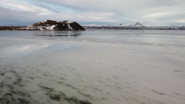 Low aerial flight drone over frozen lake to volcano in Iceland