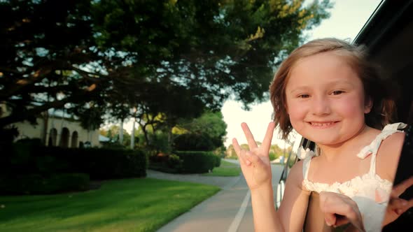 Teen Girl Ooking Out the Car Window and Waving His Hand