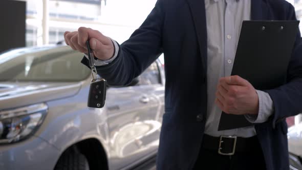 Auto Sale Center, Professional Car Seller Guy Holds in Hands Keys To New Automobile for Sale in