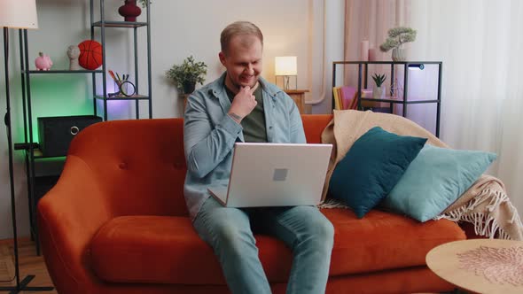 Caucasian Man Sitting on Sofa Opening Laptop Pc Starting Work Elearning Online in Room at Home