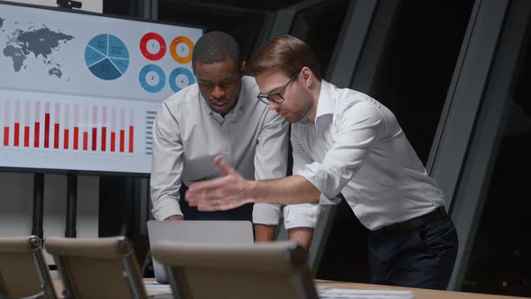 Young business people working with statistics using laptop and multimedia tv