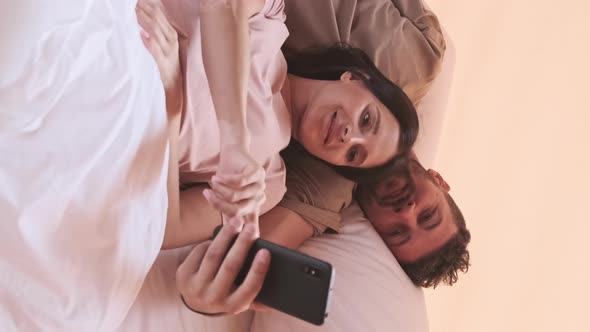 Couple Using Phone in Bed