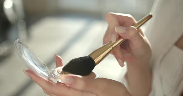 Beautiful Girl Doing Makeup with a Brush in Studio