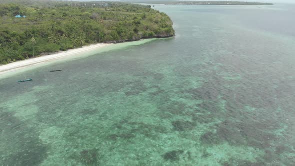 Aerial: Flying over tropical beach turquoise water coral reef, Indonesia